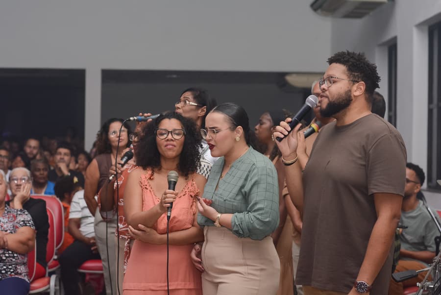 Jovens da IBVER cantando juntos com microfones durante o louvor