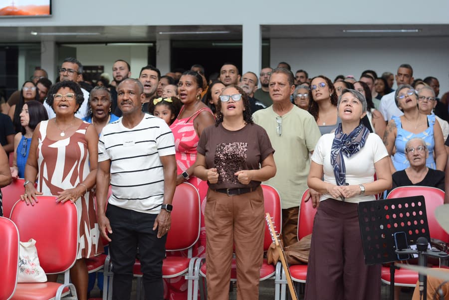 Irmãos da igreja em pé, cantando durante o culto de domingo